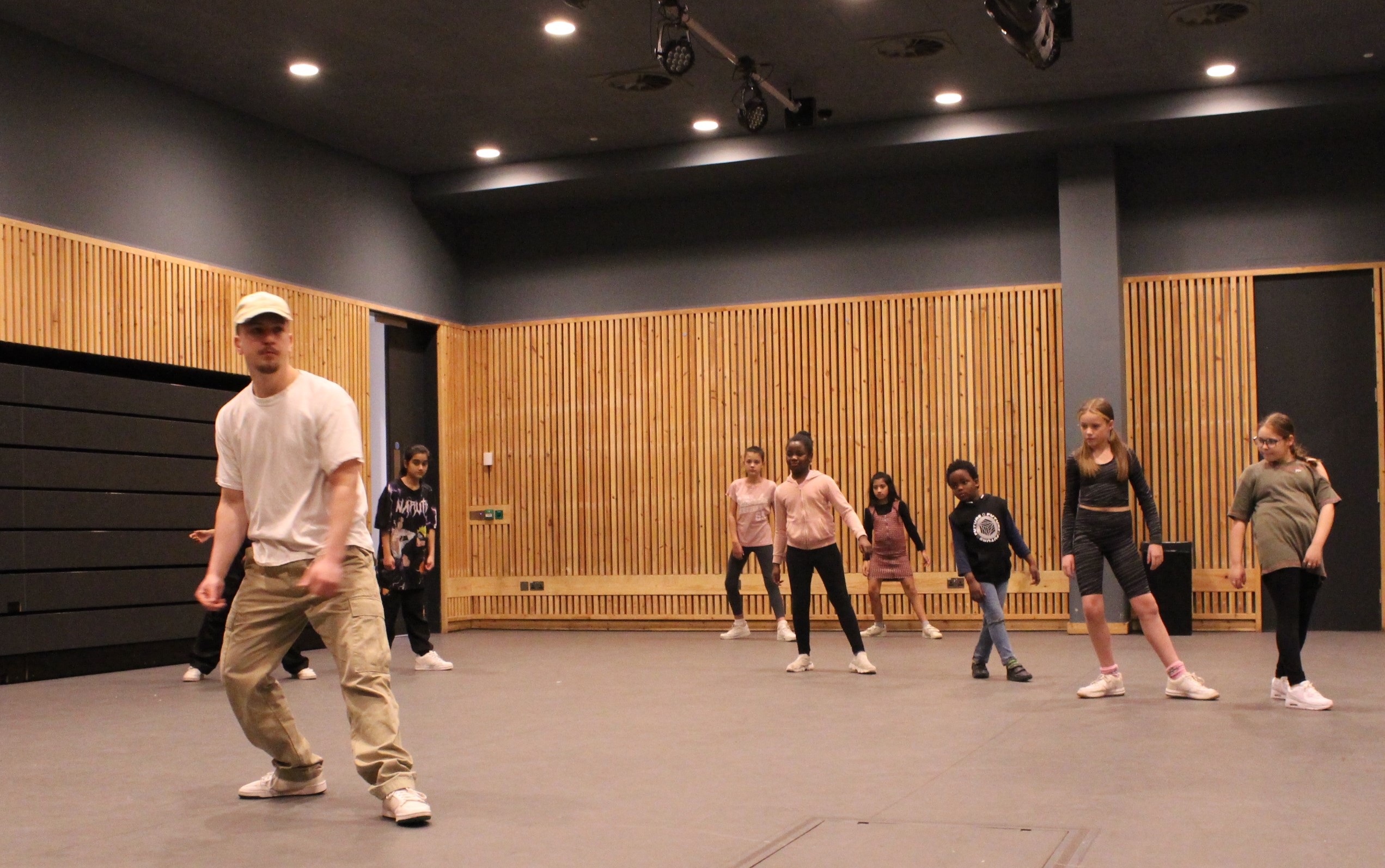 Tom Hughes Lloyd leading a group of young people in a street dance session.
