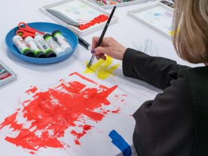 A lady works on a red and yellow abstract painting.