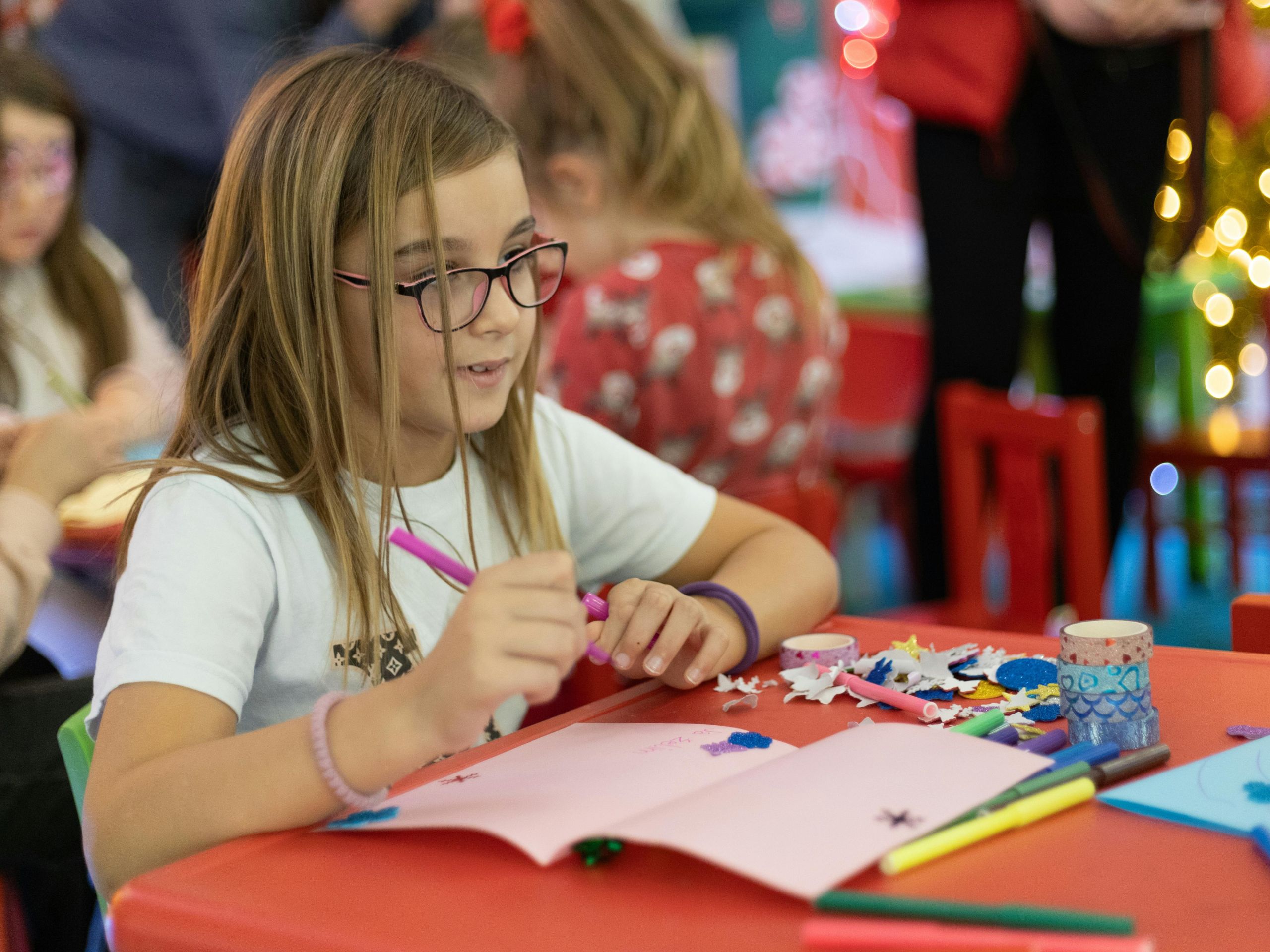 A girl with long hair and classes working on a craft project.