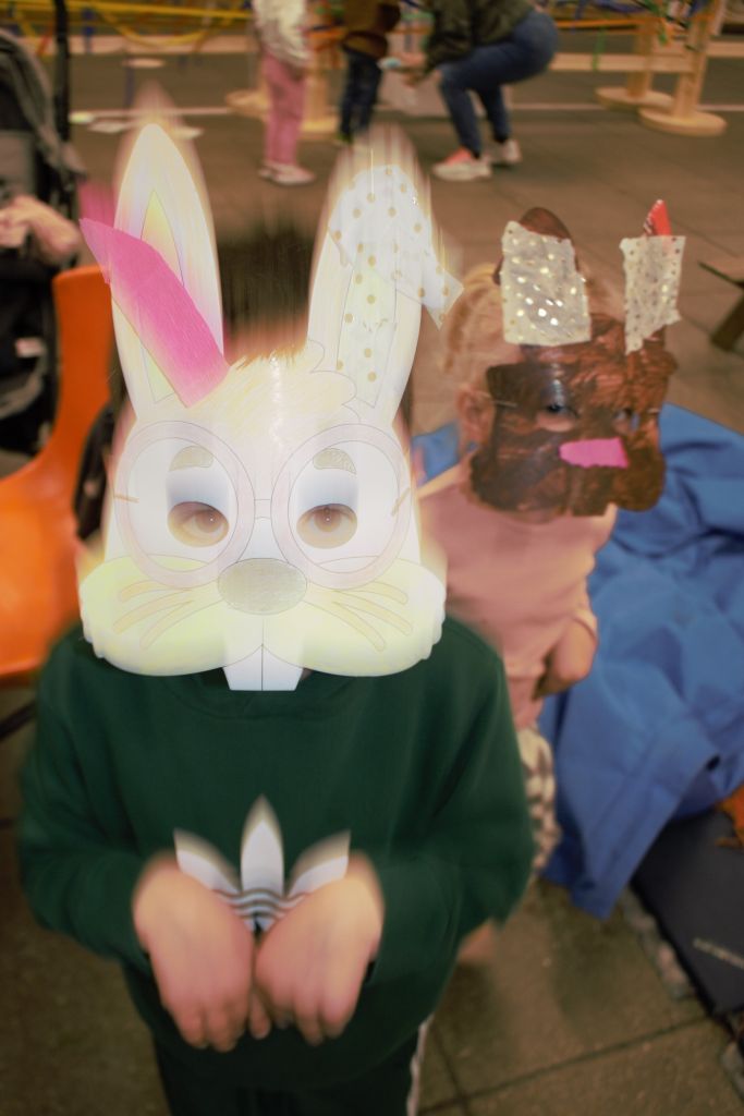 Two children in homemade bunny masks appear to blurred as they playfully bounce around.