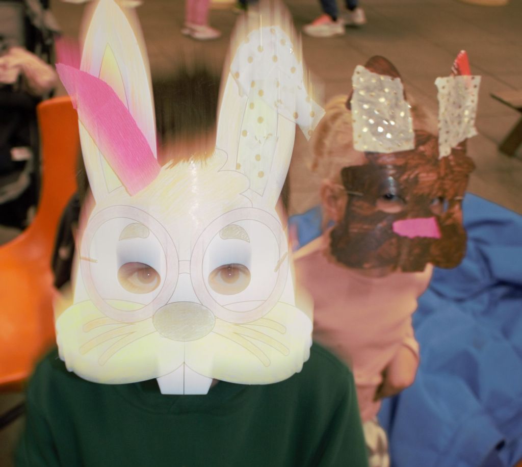 Two children in homemade bunny masks appear to blurred as they playfully bounce around.
