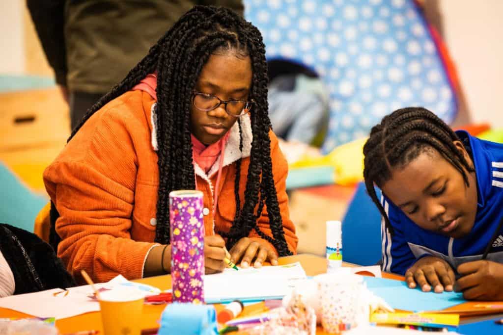 Two young people participating in a North East Wales Multicultural Hub drop-in craft activity,